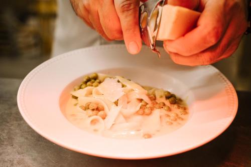 a person pouring food into a bowl of soup at Conimbriga Hotel do Paço in Condeixa a Nova