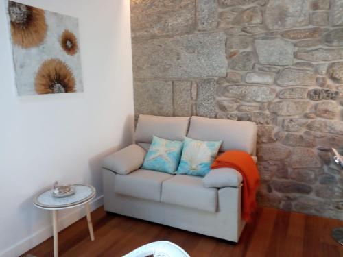 a living room with a couch and a stone wall at O Iniño casita rural costera in O Grove