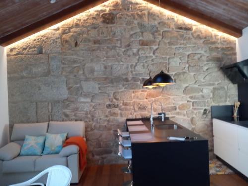 a living room with a stone wall with a table and a couch at O Iniño casita rural costera in O Grove