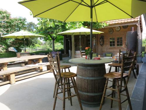 a patio with a table and chairs and an umbrella at Hoeve Chartreuse in Bruges