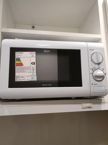 a microwave sitting on a shelf in a kitchen at Del Cerro Departamentos in El Calafate