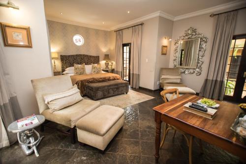 1 dormitorio con 1 cama y sala de estar con mesa en Godiva Spa & Guesthouse en Groblersdal