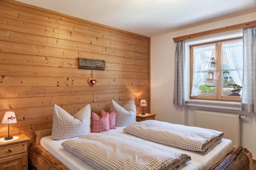 two beds in a bedroom with a wooden wall at Ferienwohnung Edelweiß in Grainau