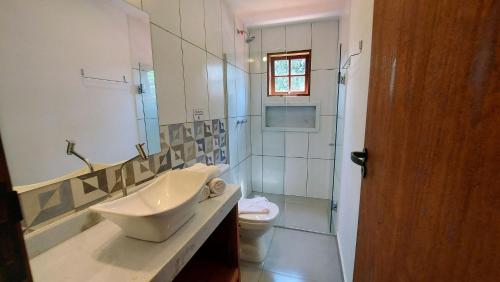 Un baño con lavabo, inodoro y ducha. en Algodão - Novo Flat com Piscina, 50mts da praia, churrasqueira privativa, ar con, wi-fi, netflix, garagem, en Paraty