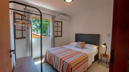 Un dormitorio pequeño con una cama y una ventana. en Algodão - Novo Flat com Piscina, 50mts da praia, churrasqueira privativa, ar con, wi-fi, netflix, garagem, en Paraty