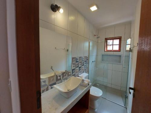 ein Badezimmer mit Waschbecken, Toilette und Dusche in der Unterkunft Cotia - Novo Flat com Piscina, 50mts da praia, churrasqueira privativa, ar con, wi-fi, netflix, garagem in Paraty