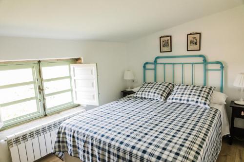 a bedroom with a bed with a checkered blanket and two windows at Saramagoso in Meis