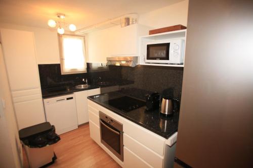 une petite cuisine avec une cuisinière et un micro-ondes dans l'établissement Villa Mama Cocha 8 minutes à pied des plages, à Sanary-sur-Mer