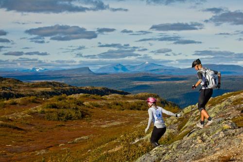 a man and a woman walking on a mountain at Hotell Funäsdalen in Funäsdalen