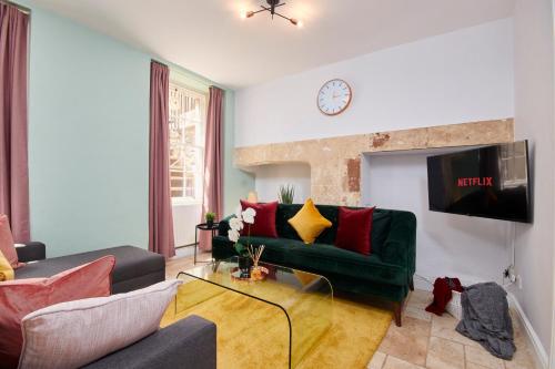 sala de estar con sofá verde y reloj en Wonderful Apartment in Bath wGarden - Sleeps 8 en Bath