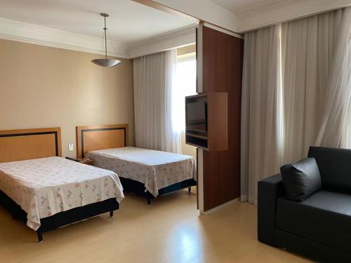 um quarto com duas camas e uma televisão e um sofá em Flat, Savassi Condomínio Century em Belo Horizonte
