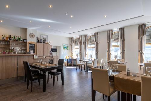 a dining room with tables and chairs and windows at Hotel Mettlacher Hof in Mettlach