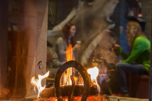 a woman is sitting in front of a fire at Hotell Funäsdalen in Funäsdalen