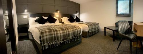 a hotel room with two beds and a chair at Siberia Bar & Hotel in Aberdeen