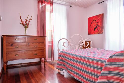 ノルデスチにあるCasa D'Eiraのベッドルーム1室(ドレッサー、ストライプ毛布付きのベッド1台付)
