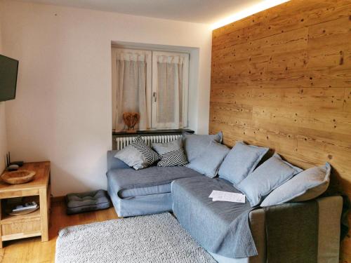 a living room with a blue couch and a wooden wall at Casa Lana in Chiesa in Valmalenco