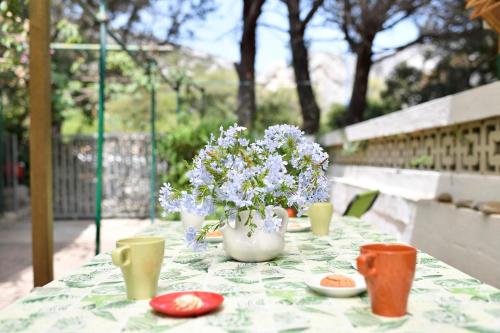 a table with a vase of flowers and cups on it at Appartamento Pini in Cala Gonone
