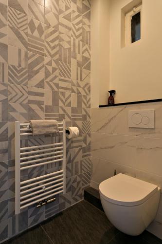 a bathroom with a toilet and a tile wall at Stadsslaperij B&B in Tilburg