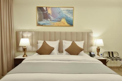 a bedroom with a large white bed with two lamps at Saray Deluxe Hotel Apartments in Abu Dhabi