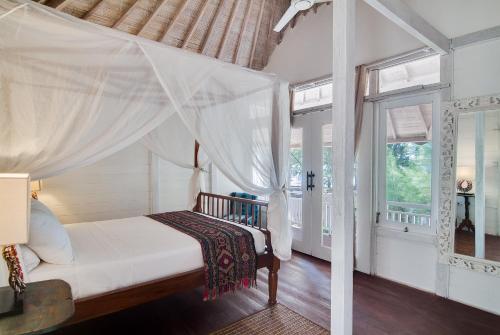 1 dormitorio con 1 cama con dosel en Coral Flora Villa Beach Front, en Gili Trawangan