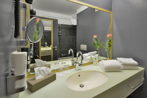 a bathroom with a sink and a mirror at Landhotel Schnuck in Schneverdingen