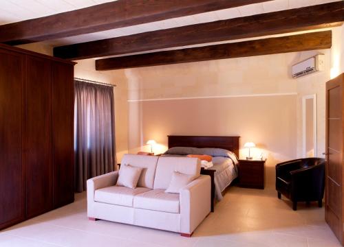 a bedroom with a bed and a white chair at Girgentina in Xagħra