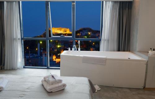bañera blanca en una habitación con ventana grande en BEAUTIFUL PEOPLE SUITES ATHENS ACROPOLIS VIEW, en Atenas