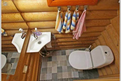 a bathroom with a sink and a toilet and towels at Järvenrantamökki Himoksella poreammeella in Jämsä