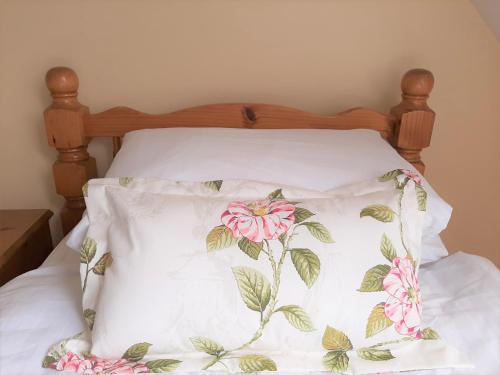 a bed with a pillow with pink flowers on it at Abhainn Ri Cottages in Blessington