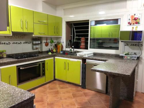 una cocina con armarios de color verde lima y encimeras de granito en Apartment Nazaha for families only en Tánger