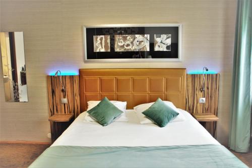 um quarto com uma cama com almofadas verdes e brancas em The Originals City, Archotel, Sens (Inter-Hotel) em Sens