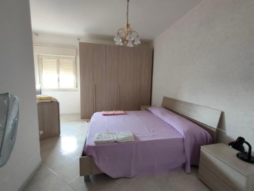 sypialnia z fioletowym łóżkiem i oknem w obiekcie Casa vacanze Marsala da Andrea w mieście Marsala