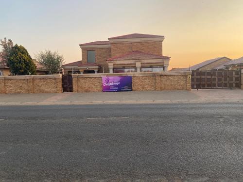 a building with a purple sign on a brick fence at Nimza K Guesthouse in Kimberley