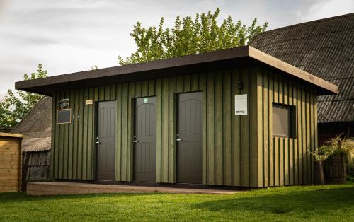 a green shed with four doors and a black roof at Kupiškėnų Starkėnas in Palėvenėlė