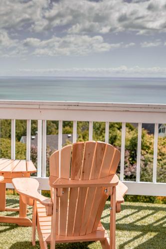 a wooden chair sitting on a porch with the ocean at Auberge Des 3 Canards in La Malbaie