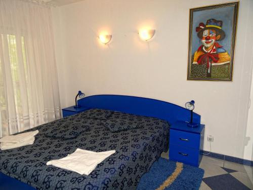 a bedroom with a blue bed and a painting on the wall at Club Topaz Apartments in Neptun