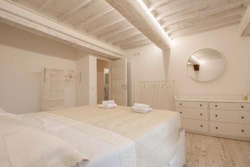 een witte slaapkamer met een groot bed en een spiegel bij CASA ALICE - Elegant in the centre of the city in Siena