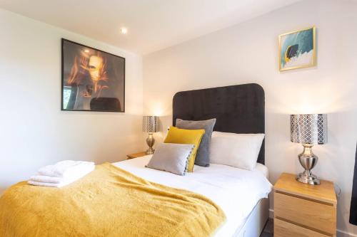 a bedroom with a bed with a yellow blanket on it at Modern 2 bed BroomPark/Central apt. with Parking in Glasgow