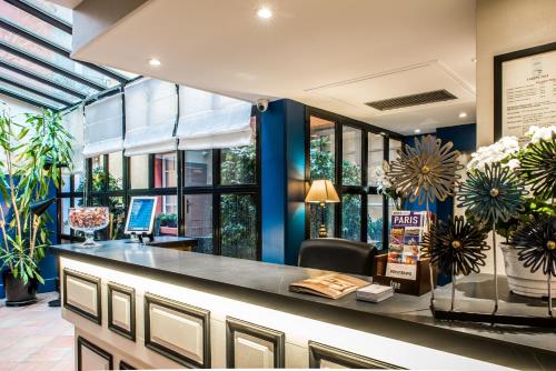 a lobby with a counter with flowers on it at Hôtel Jardin Le Bréa in Paris