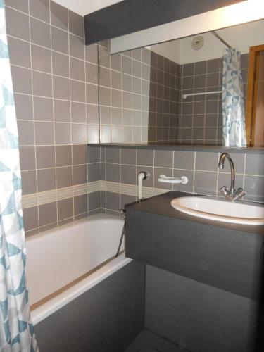 une salle de bain avec un lavabo, une baignoire et un miroir dans l'établissement travelski home classic - Résidence Carène, à Belle Plagne