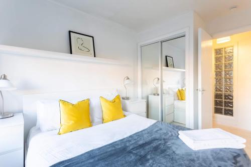een witte slaapkamer met een bed met gele kussens bij St Vincent Central Apartment in Glasgow