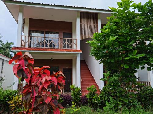 a house with a balcony and a tree at Hotel Exotica Squares in Neil Island