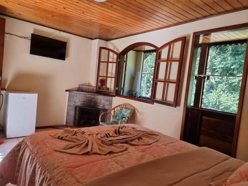 Schlafzimmer mit einem Bett, einem Kamin und einem Spiegel in der Unterkunft Chalés Palmeira Azul in Visconde De Maua