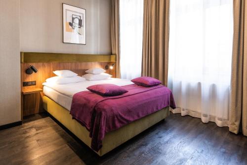 Cette chambre comprend un lit avec des draps et des oreillers violets. dans l'établissement Liebeskind Boutique Hotel, à Cracovie