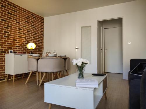 - un salon avec un vase de fleurs sur une table basse dans l'établissement Appart'HomeCity - Rouen Vauban, à Rouen