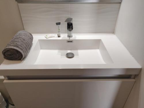 un lavabo de salle de bain blanc avec une serviette dessus dans l'établissement Appart'HomeCity - Rouen Vauban, à Rouen