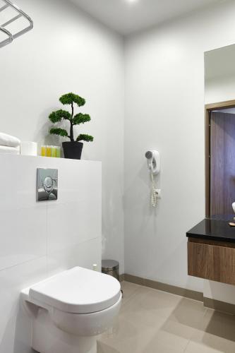 a bathroom with a toilet and a plant on the wall at Wronia Business Residence by BookingHost in Warsaw