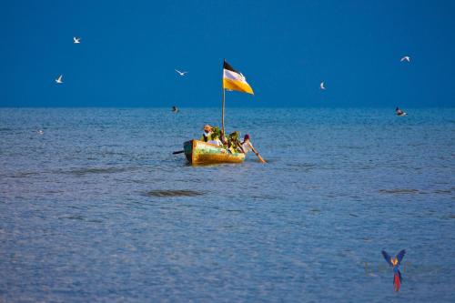 a boat with a flag in the middle of the water at Pelican Beach Resort South Water Caye in Dangriga