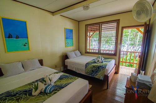 a hotel room with two beds and a window at Pelican Beach Resort South Water Caye in Dangriga