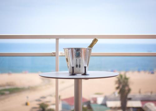 a toothbrush in a cup on a table next to a beach at Hotel Sorra Daurada Splash in Malgrat de Mar